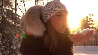 慢镜头:在神奇的冬天，年轻女子在夕阳下吹着雪花视频素材模板下载
