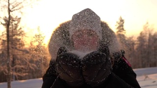 慢镜头:在神奇的冬天，年轻女子在夕阳下吹着雪花视频素材模板下载
