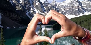 近距离的手使心形框架上的山湖景观