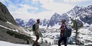 一对在加拿大落基山脉徒步旅行的夫妇到达山顶并击掌庆祝