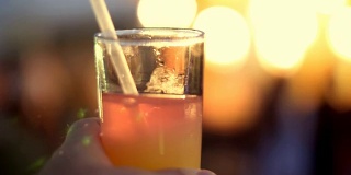 在鸡尾酒会上，一杯饮料用冰装在一个用管的玻璃杯里，在光线的拱檐下，灯光闪烁。原版酒精鸡尾酒和非酒精鸡尾酒