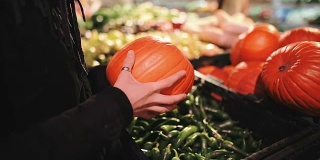 美丽的女孩正在超市里的蔬菜摊上挑选南瓜，作为秋季节日，比如万圣节