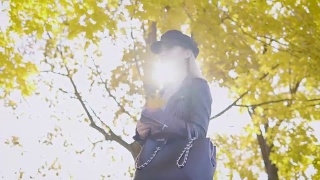 秋日里，体贴的金发美女漫步在公园里，拿着胸前泛黄的枫叶，翘起镜头视频素材模板下载