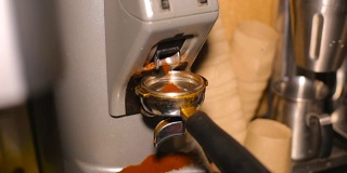 在咖啡馆酒吧的后面，咖啡研磨机将研磨好的咖啡倒入杯中