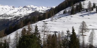 冬季无人机建立雪山下的森林森林山谷。雪山在户外自然。一边飞行。旅行探索阿尔卑斯山，4k俯视图视频
