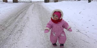 可爱的小女孩在冬天的雪地上快步走着。FullHD