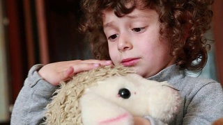 孩子抚摸着玩具羔羊视频素材模板下载