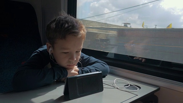 孩子戴着耳机在火车上看卡通