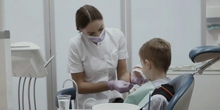 牙医在一个牙齿模型上教一个小男孩如何用牙刷刷牙