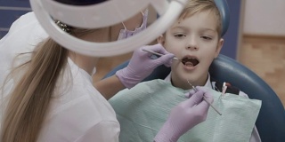 牙医用有棱角的探针和镜子检查小男孩的牙齿
