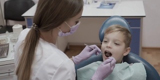 牙科医生用有棱角的探针和镜子检查小男孩的牙齿