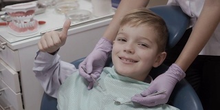 一个微笑的小男孩在牙医椅上竖起大拇指