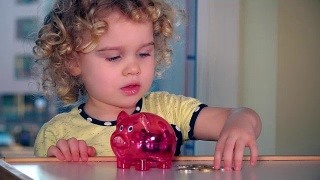 可爱的小女孩将欧元硬币插入储蓄罐视频素材模板下载