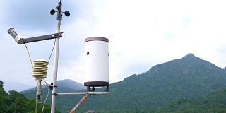 气象气象站天线与气象传感器，灰色多云天空和森林背景。