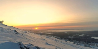 航拍:在金色的日出中，穿着雪鞋的运动女性走向雪山