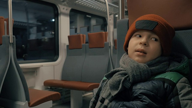 男孩在夜间行驶的通勤火车上