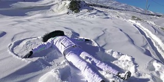 年轻女子摔倒了，做了个雪天使。超高清4K摄像机库存镜头