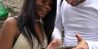 一名巴西图皮瓜拉尼部落的游客向一名土著女孩展示手机