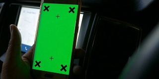 司机用绿色屏幕的智能手机在车上，色度键，多莉拍摄