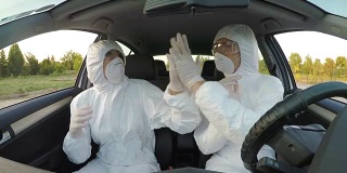 年轻有趣的科学家们坐在车里穿着危险防护服，跳着舞，充满活力，庆祝取得的成就