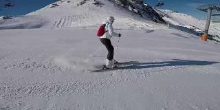 一个女人在滑雪道上滑雪，太阳和雪山。