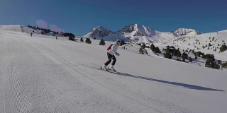 女人们在雪坡上滑雪，阳光照耀着雪山。