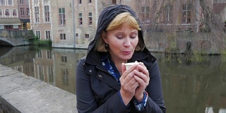 2017年5月3日，比利时布鲁日。坐在河边喝咖啡的女人。