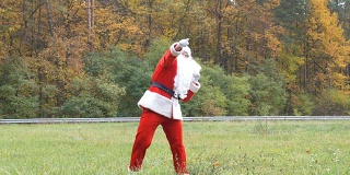 圣诞老人在草地上跳舞。背景是木头。50帧/秒