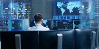 在监控室，技术人员集中监控系统的稳定性。他被显示技术数据的屏幕包围着。