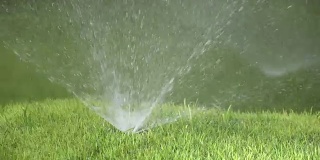 阳光明媚的日子里，草坪自动浇水系统洒水喷头的一个喷头的一个喷头的特写，慢动作