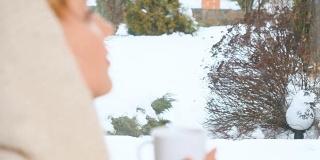 戴头巾的女孩在窗边喝茶，享受冬天
