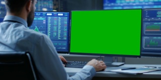 股票市场交易员在电脑上工作的肩膀视图与隔离模型绿屏和第二显示器显示数字股票与图形。在带有相关信息的后台监视器中。