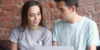 年轻情侣随意使用笔记本电脑，在网上购物选购商品
