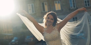 年轻美丽的新娘在老城的阳光里玩弄她的面纱