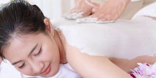 年轻女子躺在温泉床上，按摩和粘土身体面膜放松。