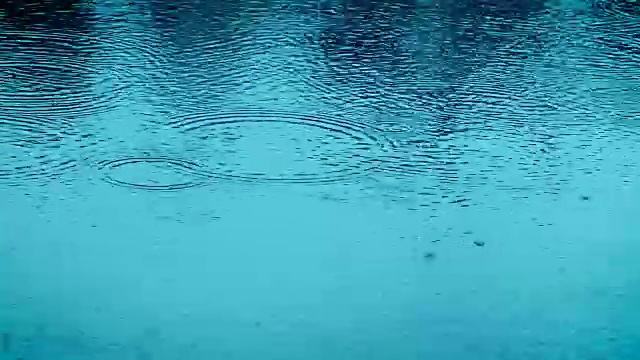 在雨季，近距离降雨水滴落在河流表面的蓝色调，4K Dci分辨率