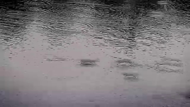 在雨季，近距离拍摄的雨滴落到河面的暗色调，4K Dci分辨率
