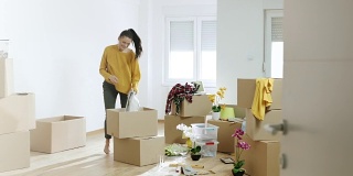一个女人在她的新公寓里拿着纸板箱