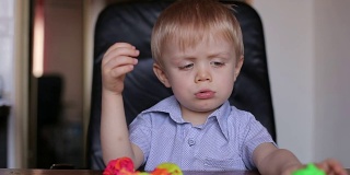悲伤的小男孩玩彩色橡皮泥。
