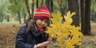 小女孩拿着一根枫树枝。