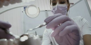 牙科医生使用角探针及镜子检查病人口腔内的牙齿