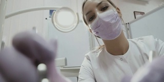 牙科医生在口腔诊所用角探针检查病人的牙齿