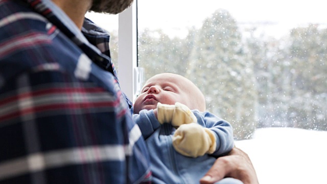 冬日里，慈爱的爸爸带着刚出生的宝宝靠近窗户