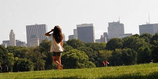 曼哈顿中央公园。以摩天大楼为背景的草地景观。一个小女孩在一张照片上用慢镜头走着