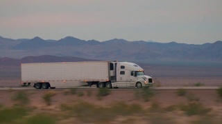 特写:货运半挂车在空旷的公路上行驶和运输货物视频素材模板下载