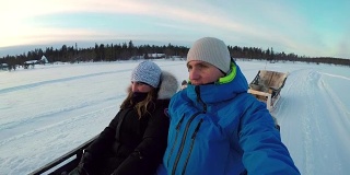 图:在冰雪覆盖的拉普兰，一对夫妇乘坐驯鹿雪橇旅游景点