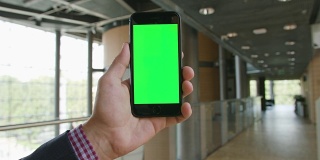 一只手拿着绿色屏幕的手机