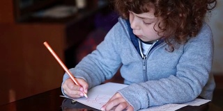孩子在玻璃桌子上用铅笔画画