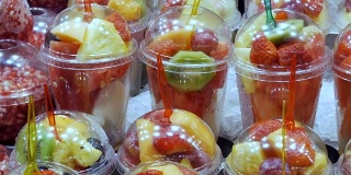 新鲜的包装在一个塑料玻璃里面，里面有西瓜，猕猴桃，梨，苹果，芒果，石榴，草莓，叉子紧紧地贴在里面