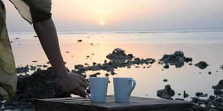 一个女孩在大海的背景上喝着咖啡